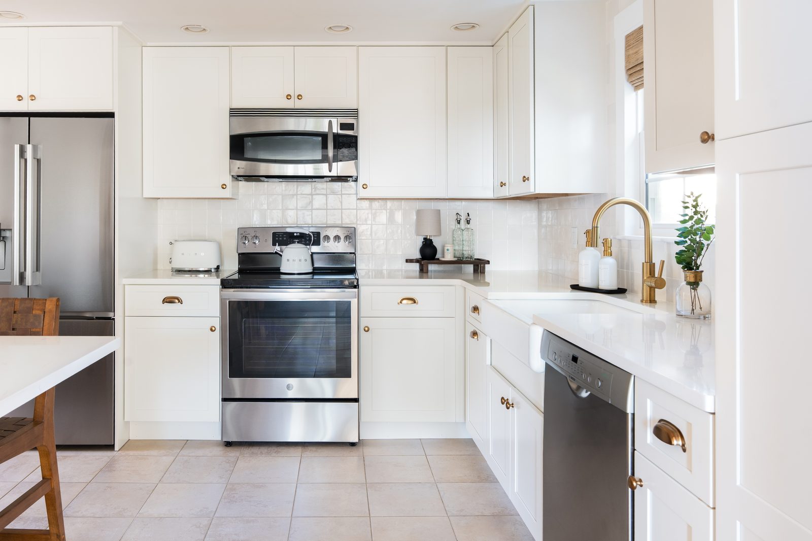 Indian Road kitchen range wall with white zellige tile backsplash, farmhouse sink, gold hardware, and stainless appliances
