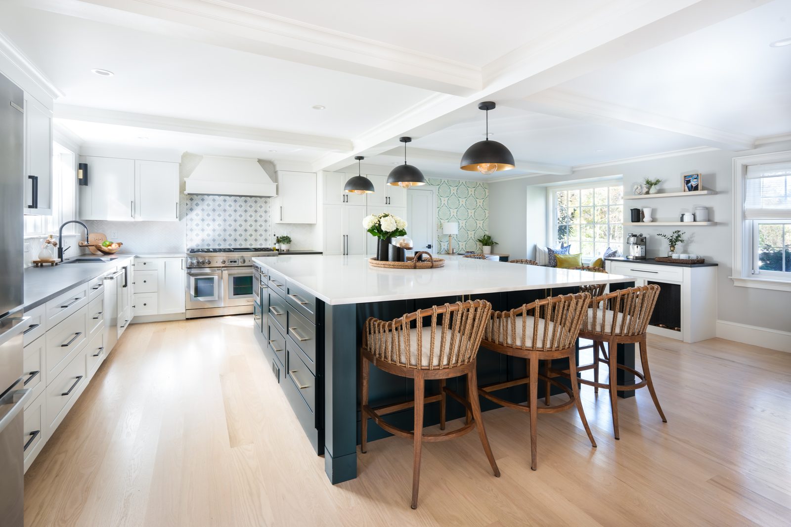 Jerusalem Road kitchen — wide view with large rich blue-green island, woven rattan bar stools, and open floor plan