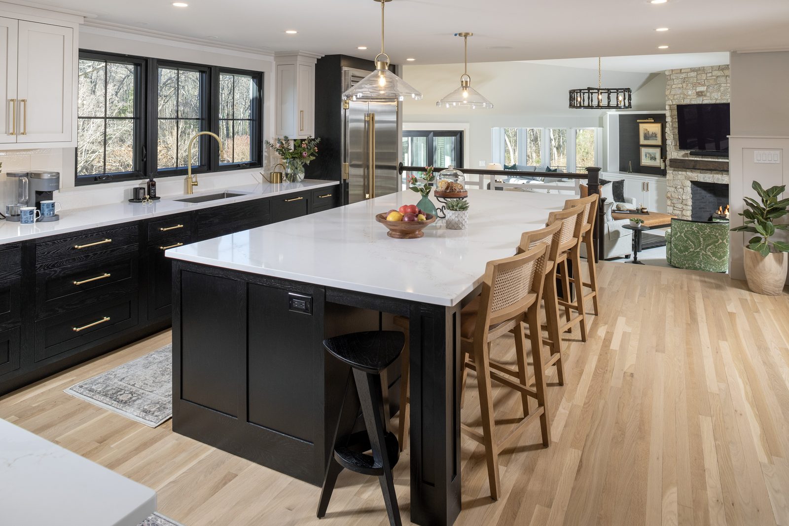 Main Street kitchen — view showing black and white two-tone cabinetry, large island, open to stone fireplace living room