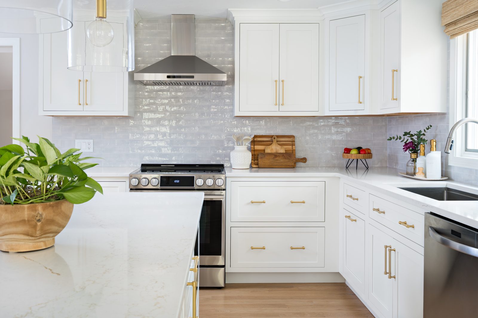 Mill Pond Lane kitchen range wall with gray zellige tile, stainless range hood, gold hardware, and marble island countertop