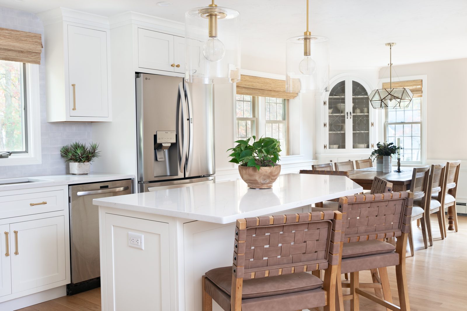 Mill Pond Lane open kitchen and dining room with large island, woven bar stools, and arched china cabinet