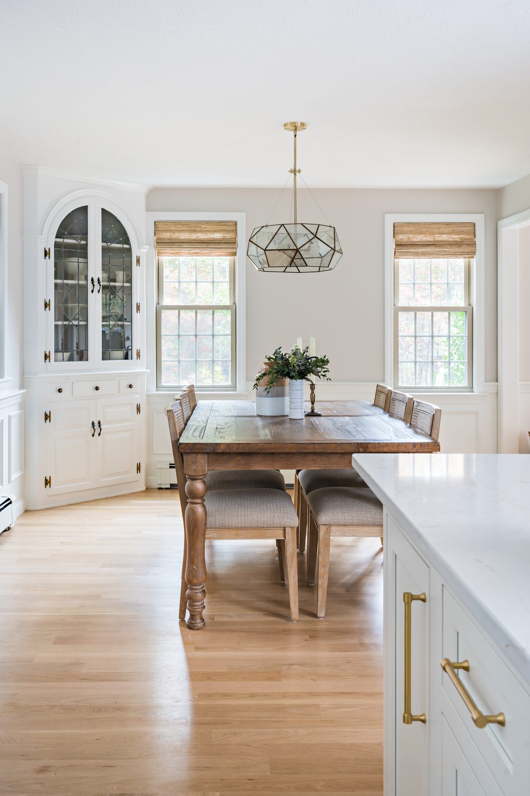 Mill Pond Lane dining room with farm table, cane chairs, arched built-in china cabinet, and gold geometric pendant