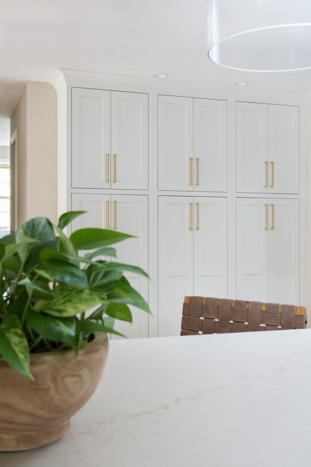 Mill Pond Lane floor-to-ceiling white shaker cabinetry wall with gold hardware and marble island countertop in foreground