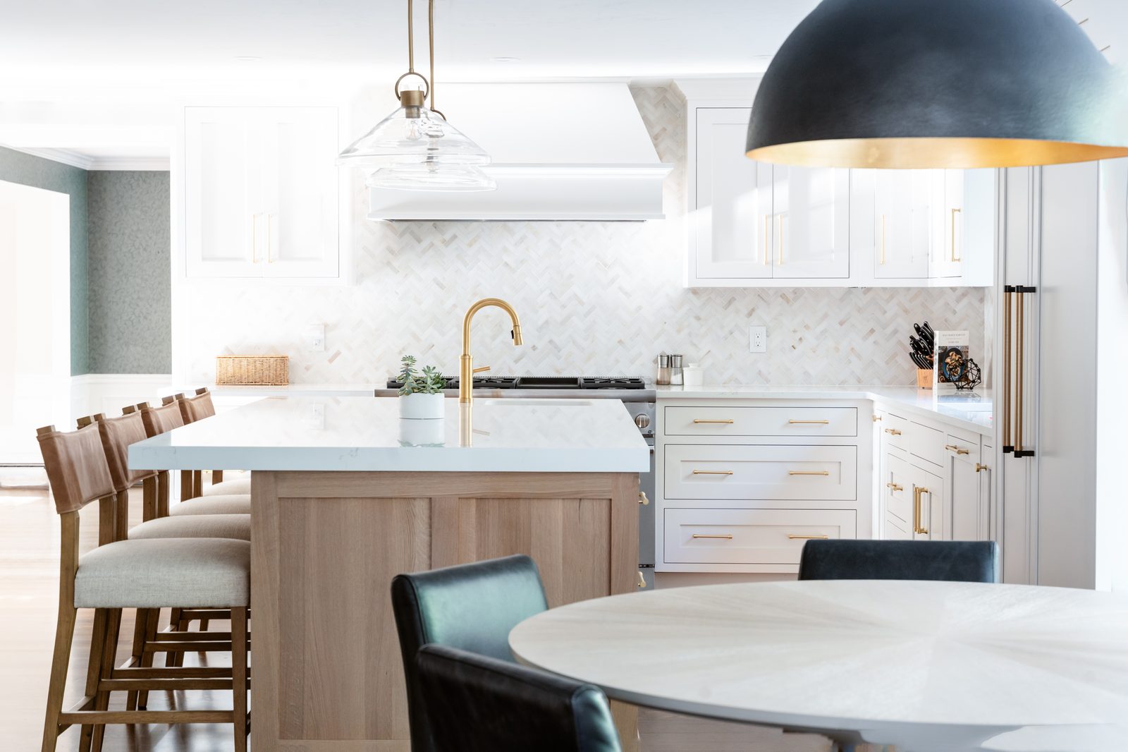 Rosewood Court kitchen — close-up of white oak island, brass faucet, and marble herringbone backsplash