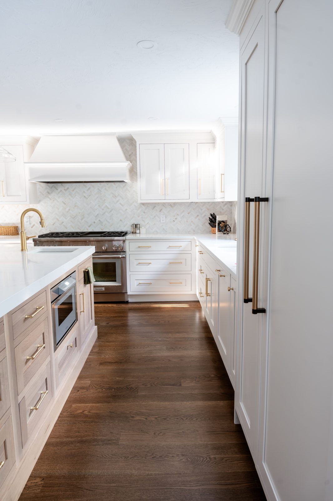 Rosewood Court kitchen corridor with white cabinetry, herringbone backsplash, brass hardware, and stainless range