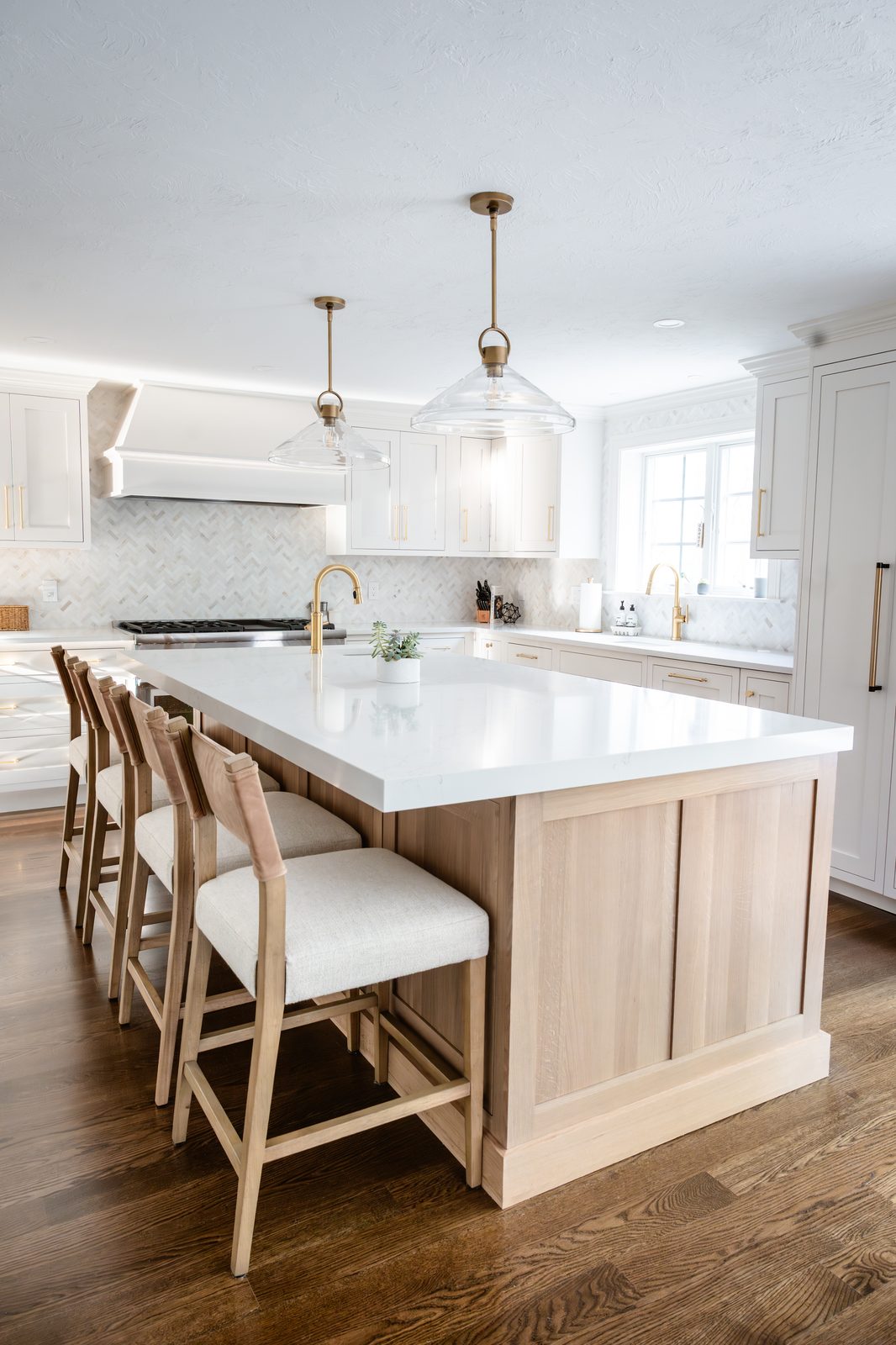 Rosewood Court kitchen with white oak island, glass pendant lights with brass fittings, and all-white cabinetry